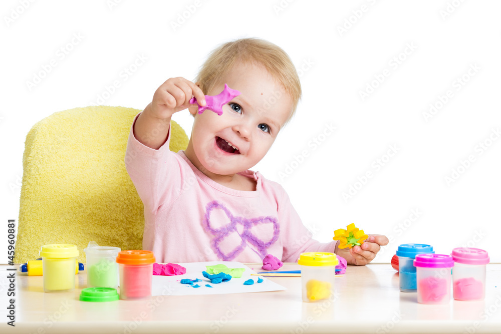 Happy little kid sitting at table and playing with colorful clay Happy little kid sitting at table and playing with colorful clay