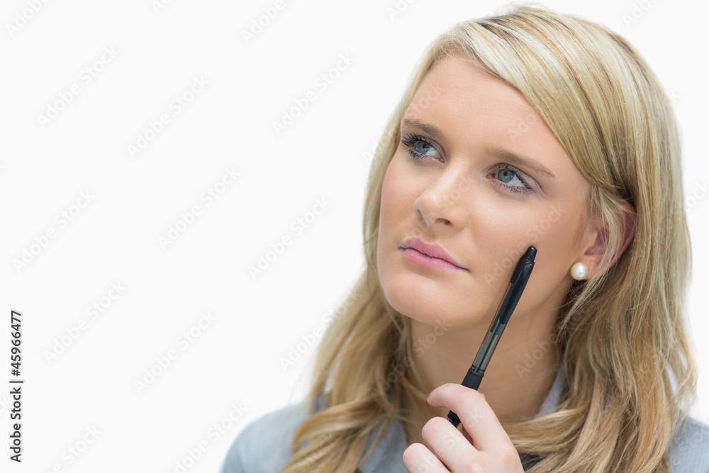 Woman looking up while holding a pen Woman looking up while holding a pen