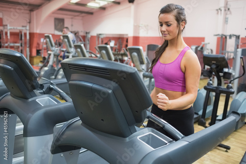 Woman running on a treadmill in a gym looking down