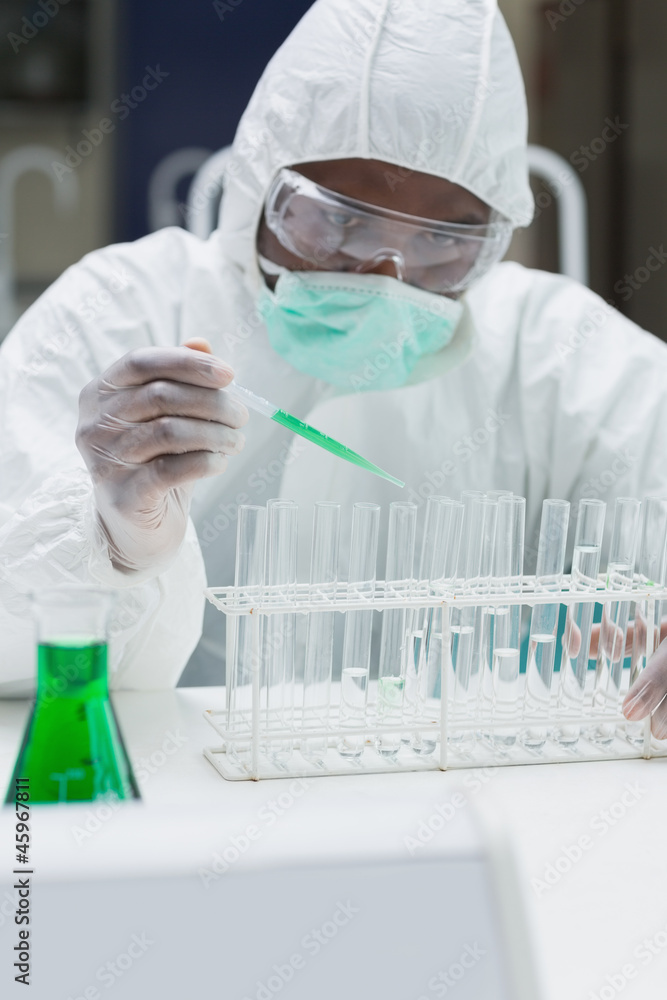 Fototapeta premium Chemist adding green liquid to test tubes