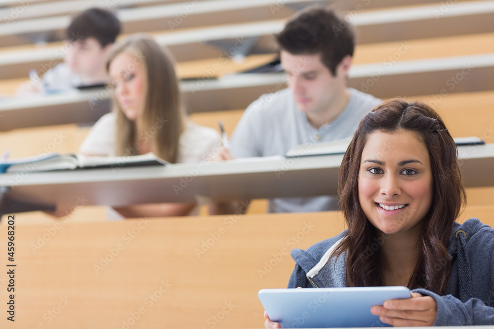 Smiling student taking notes with tablet pc Smiling student taking notes with tablet pc