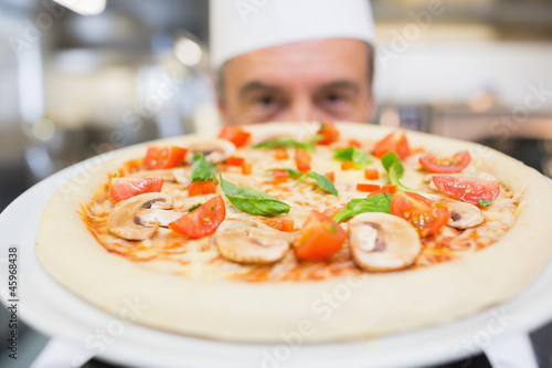 Cook presenting a pizza