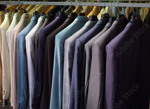 colorful male suits in row in a hanger