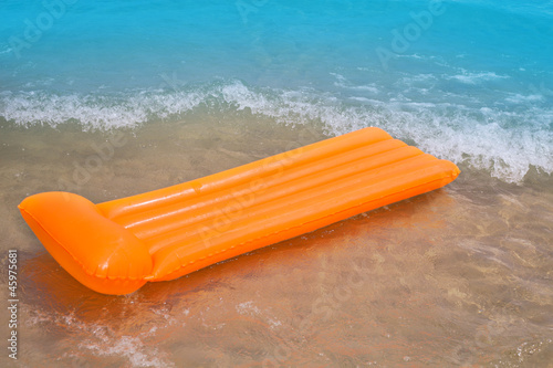 Beach shore with orange floating lounge and waves © lunamarina