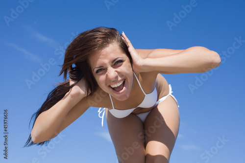 Young woman in swimwear crying against the sky