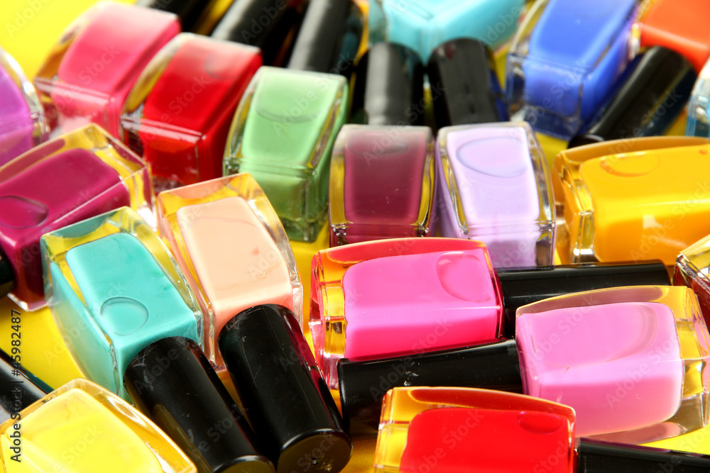 Fototapeta premium Group of bright nail polishes, on yellow background