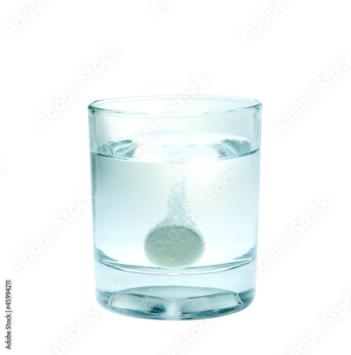 Effervescent tablet splashing into glass full of water