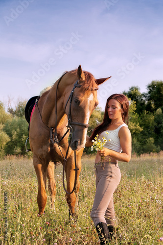 Young girl and horse on a summer meadow