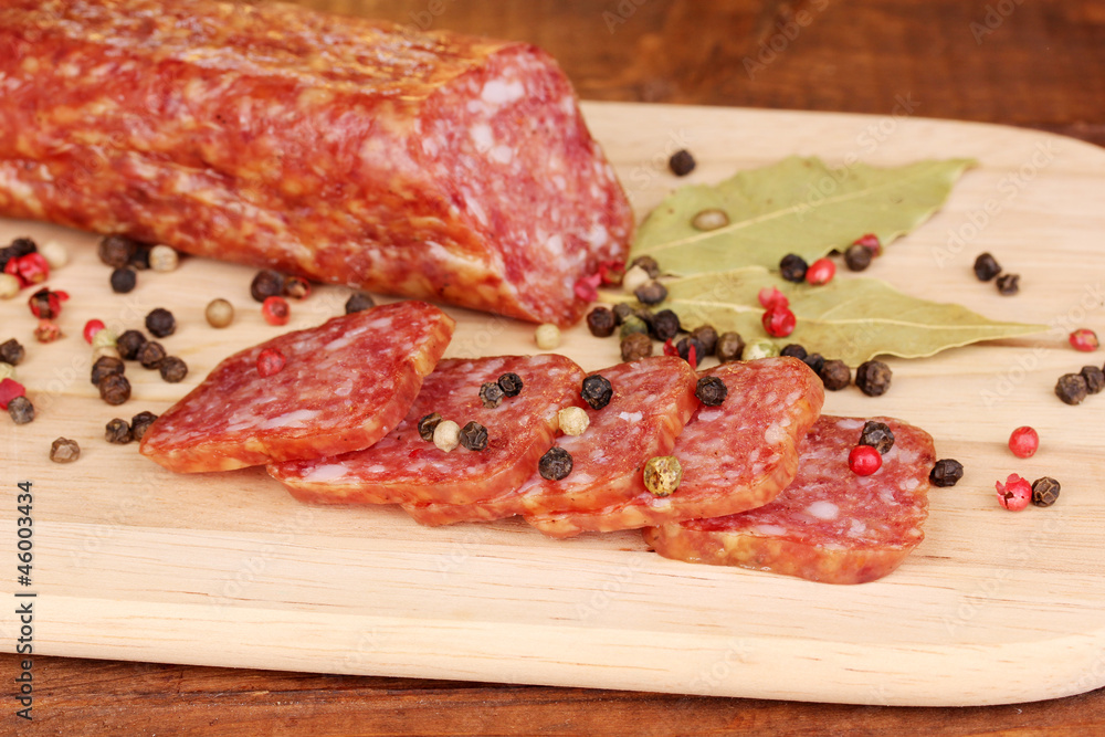 Tasty sausage on chopping board on browm background Tasty sausage on chopping board on browm background