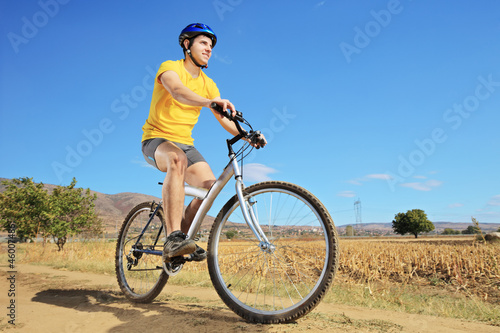 A young male in yellow shirt riding a bike
