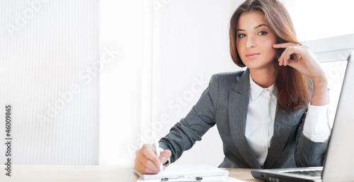 Beautiful young business woman sitting relaxed at her office and photo