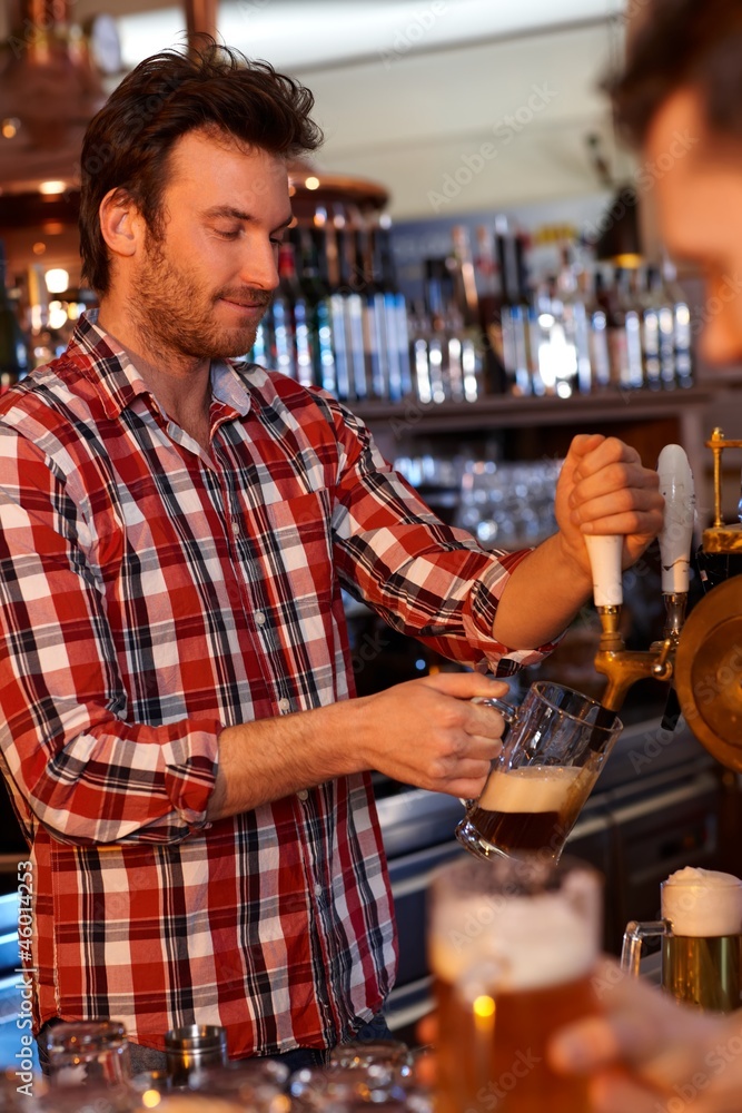 Bartender serving draught beer in bar
