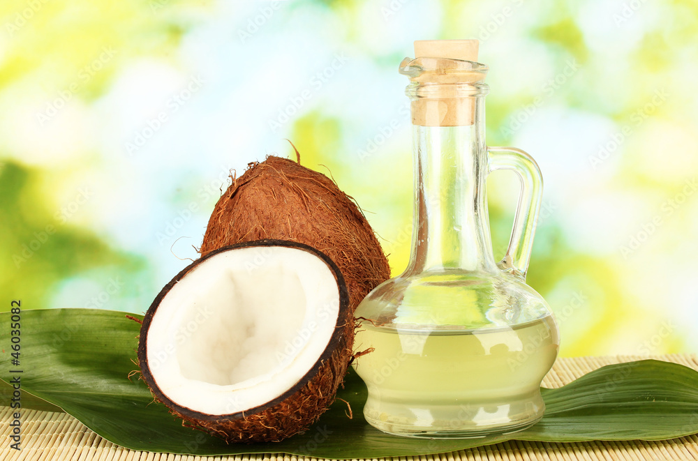 decanter with coconut oil and coconuts on green background decanter with coconut oil and coconuts on green background