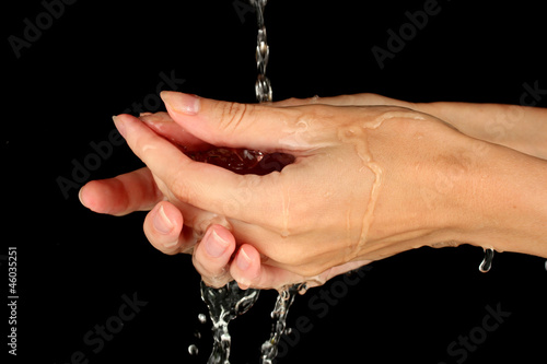 Washing hands on black background close-up