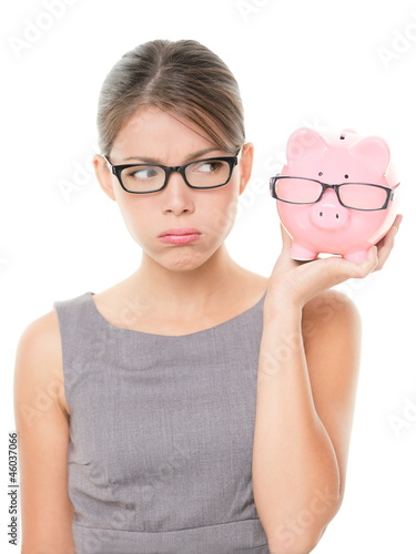 Upset woman wearing glasses holding piggy bank