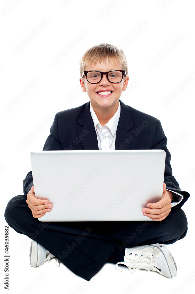 Cheerful young kid sitting on the floor with a laptop Cheerful young kid sitting on the floor with a laptop