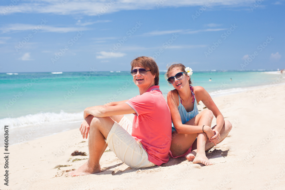 beautiful young couple sitting and having fun on beach