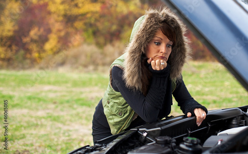 frau mit autopanne schaut in den motor photo