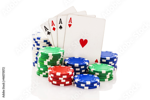 Four aces and stacks of poker chips isolated on white.