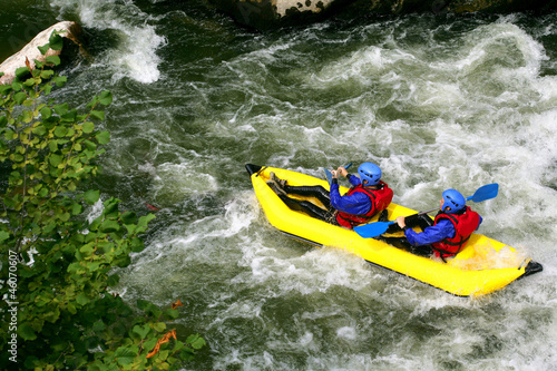 Two people kayaking down river rapids