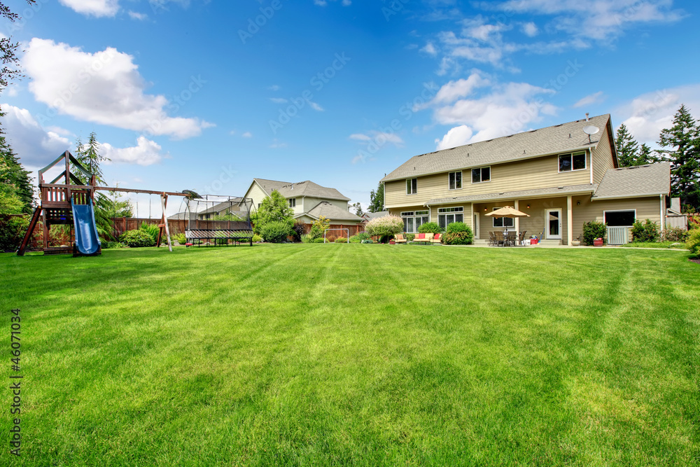 Obraz premium Large beautiful fenced backyard with play ground and house.
