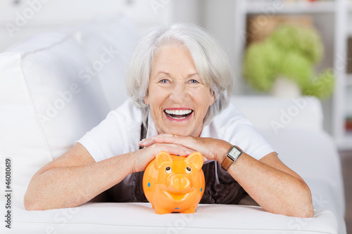 lachende seniorin mit ihrem sparschwein