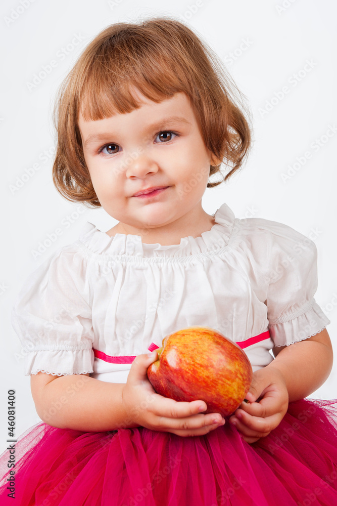 The little girl with an apple, on a gray background The little girl with an apple, on a gray background