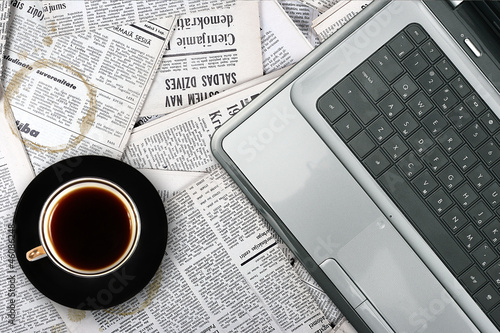 workplace with laptop and coffee cup on newspaper background