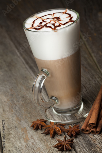 coffee cup and beans, cinnamon sticks, nuts and chocolate on woo