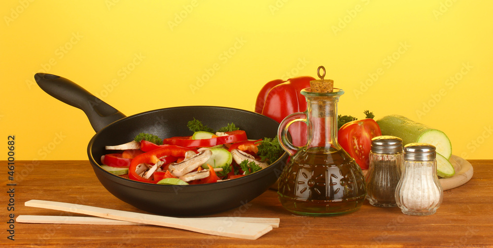 frying pan with vegetables on yellow background frying pan with vegetables on yellow background
