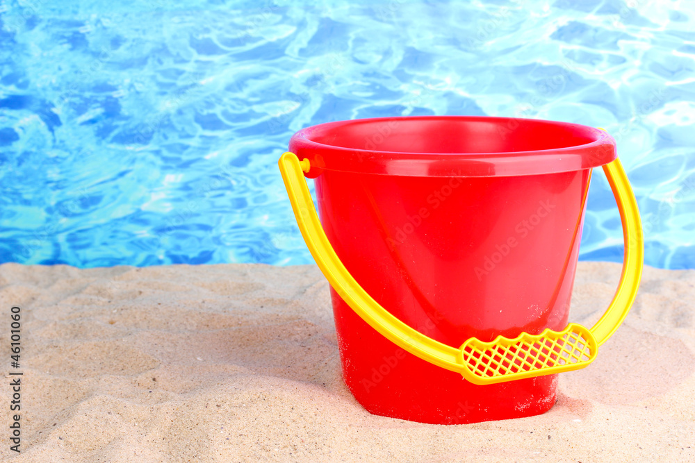 Children's bucket on sand on water background Children's bucket on sand on water background