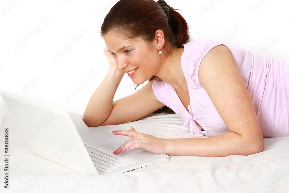 A beautiful smiling woman with a laptop lying on white A beautiful smiling woman with a laptop lying on white