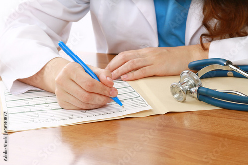 A female doctor is fiiling a prescription - close-up photo