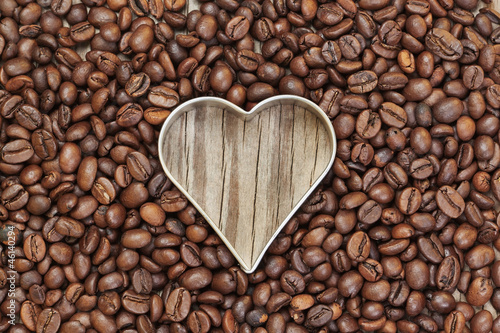 Heart shape in coffee beans on a wooden texture.