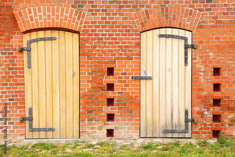 Closed wooden door in the brick wall