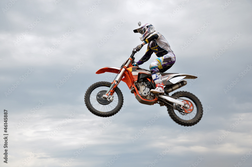 motocross rider jumps high against the sky