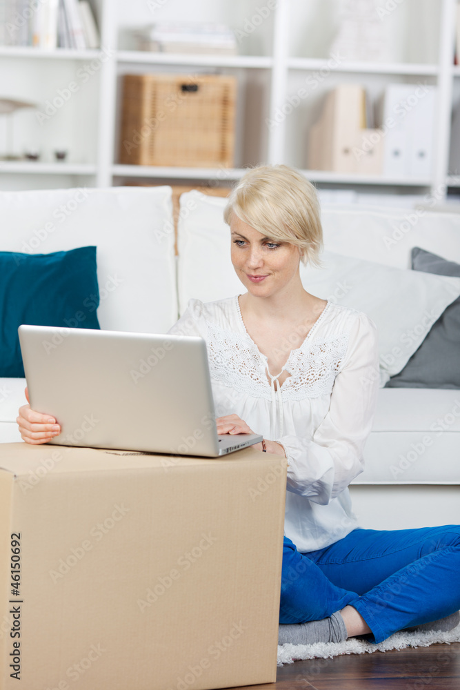 blonde frau sitzt mit laptop im wohnzimmer blonde frau sitzt mit laptop im wohnzimmer