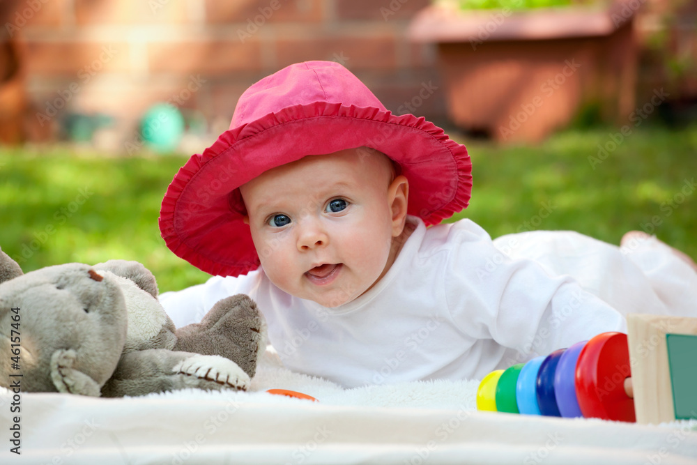Cute little baby girl playing with her toys in the garden Cute little baby girl playing with her toys in the garden