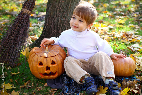 Little smiling boy with two halloween pumpkins and a broom sitti photo