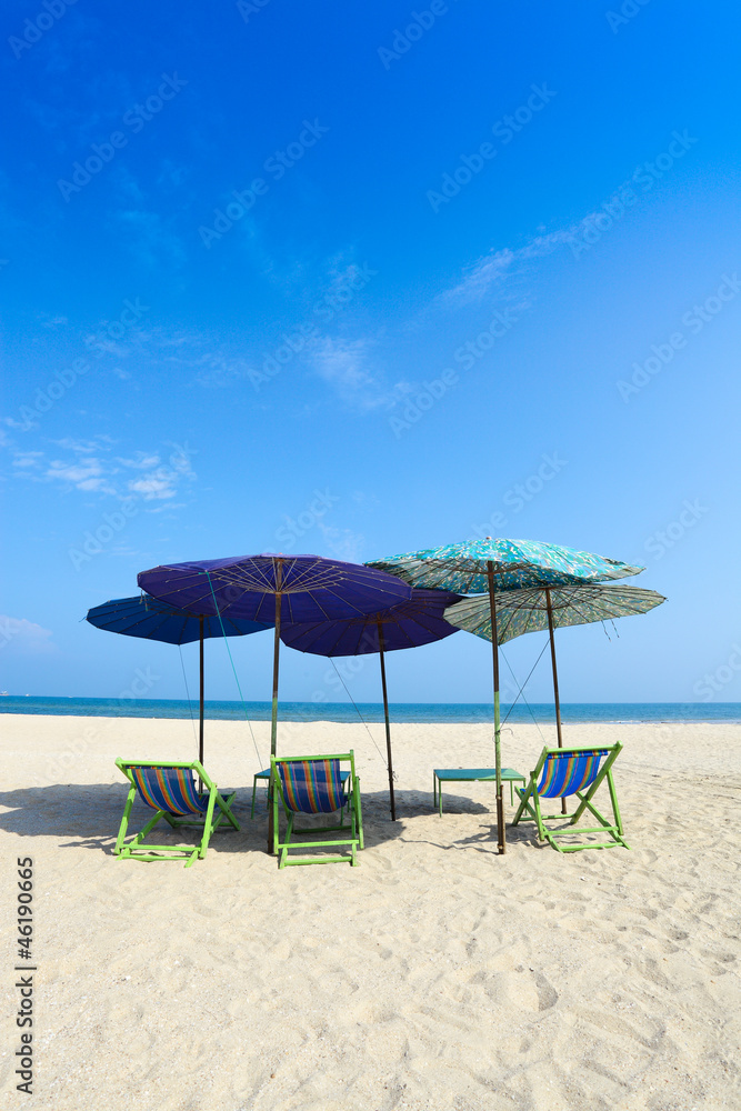 Comfort chairs and umbrella on the beach under the blue sky