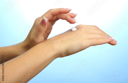 Beautiful woman hands with cream  on blue background