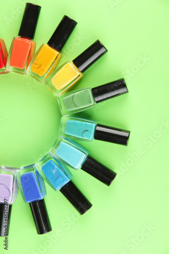 Group of bright nail polishes, on green background photo