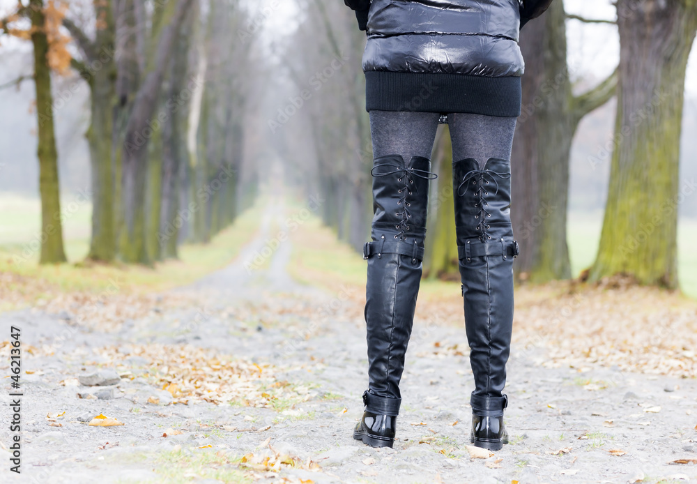 detail of woman wearing black clothes and boots in autumnal alle detail of woman wearing black clothes and boots in autumnal alle
