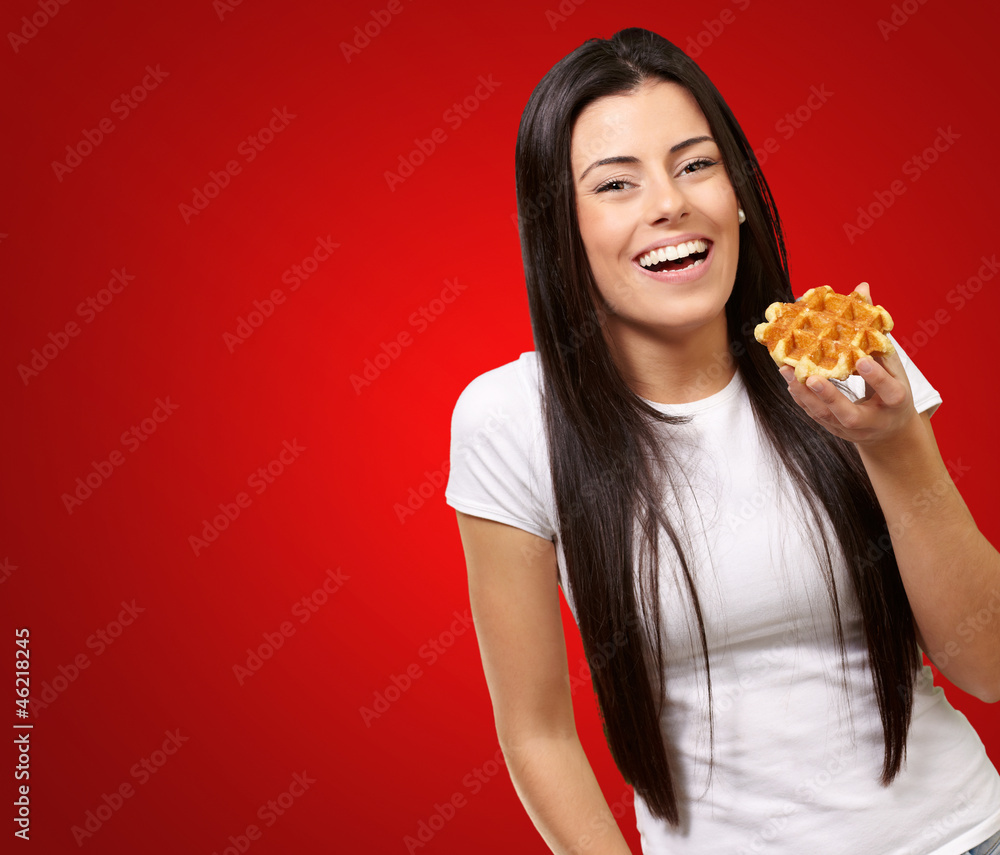 portrait of young woman holding waffle over red background