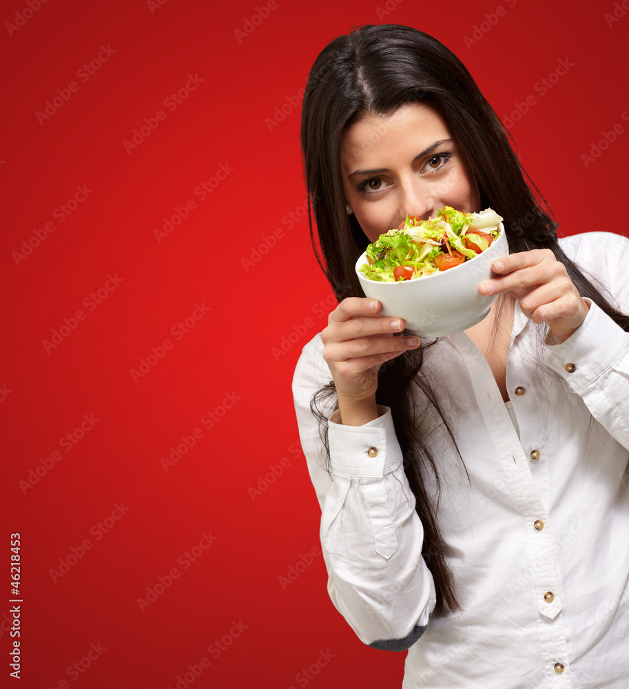 portrait of young woman holding a fresh salad over red portrait of young woman holding a fresh salad over red