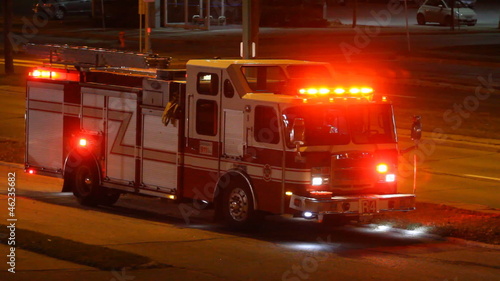 Firetruck is on the side of the road at night in the city
