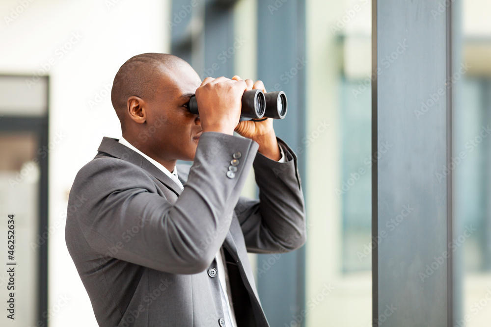 african american businessman using binoculars in office african american businessman using binoculars in office