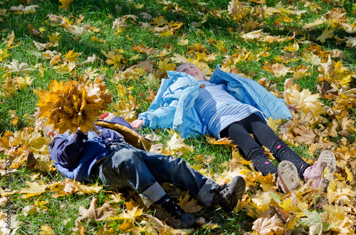 Children lying amogst autumn leaves photo