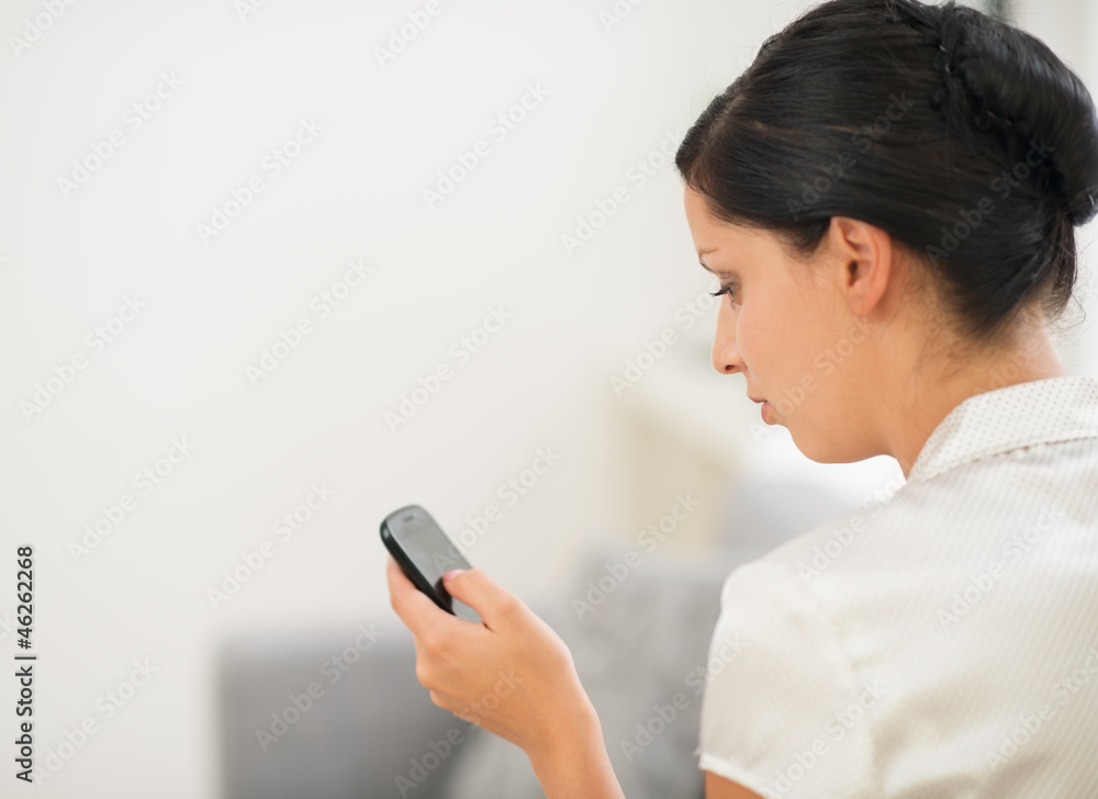 Young woman sitting on sofa and reading sms on mobile phone. Rea Young woman sitting on sofa and reading sms on mobile phone. Rea