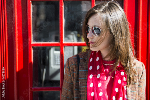 Photography Fashionable young woman leaning on red phone booth
